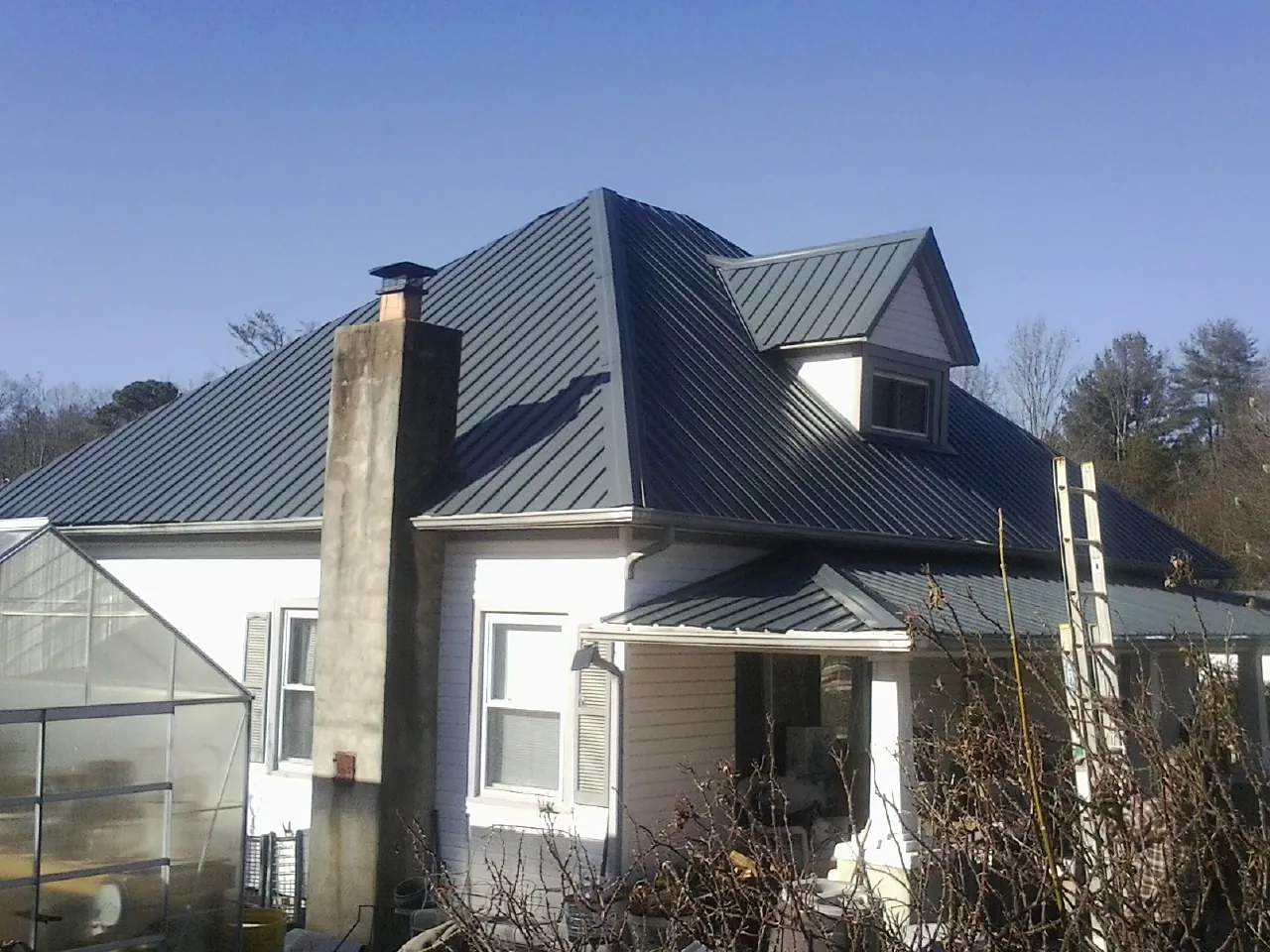 Dark blue standing seam metal roof on a white farmhouse with dormer — Slate & Tile Roof Repair by Roofing Brothers in Chico