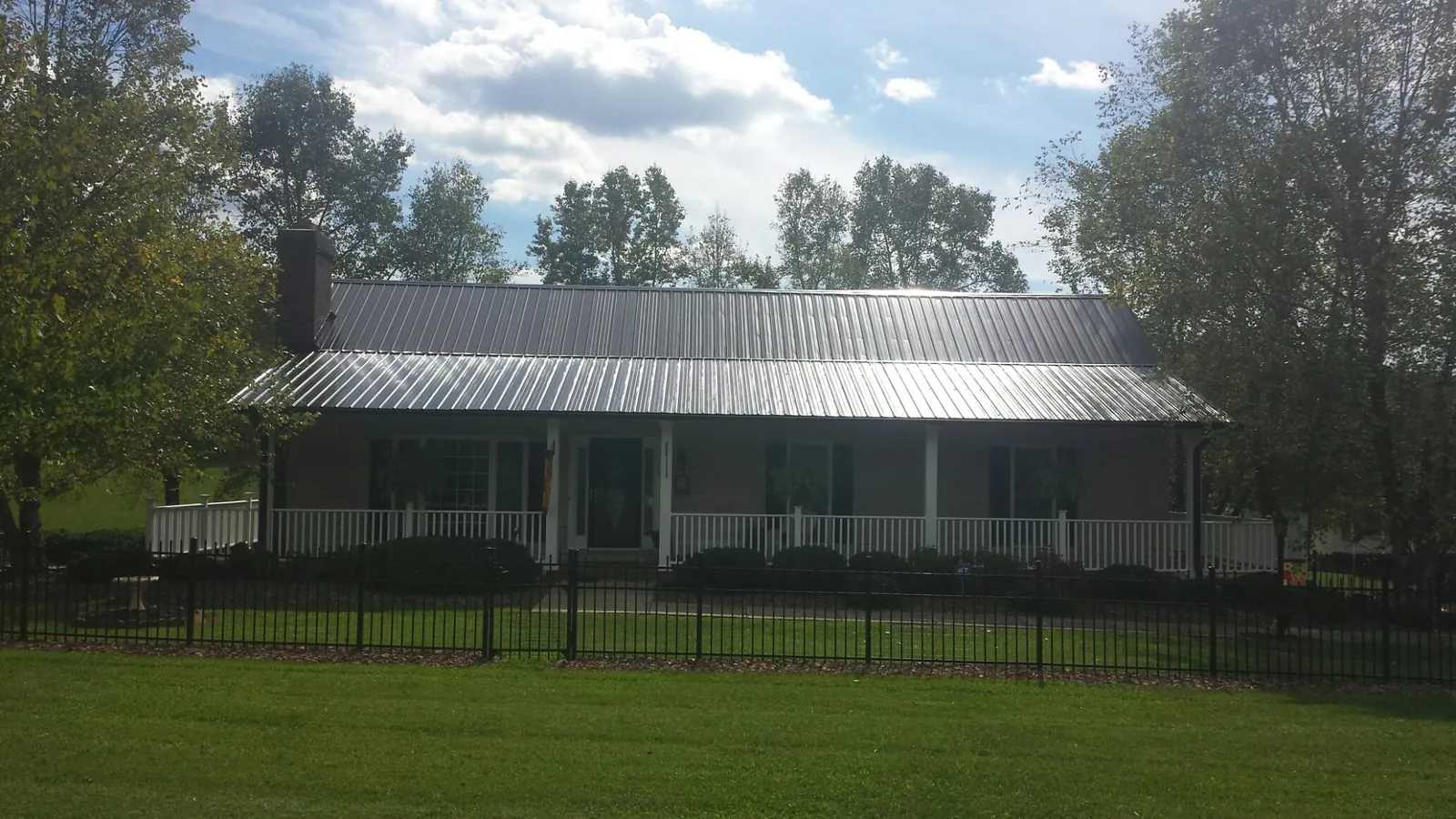 Gray metal roof on a brick ranch with a full width front porch — Gutter Guard Installation work by our crew in Chico