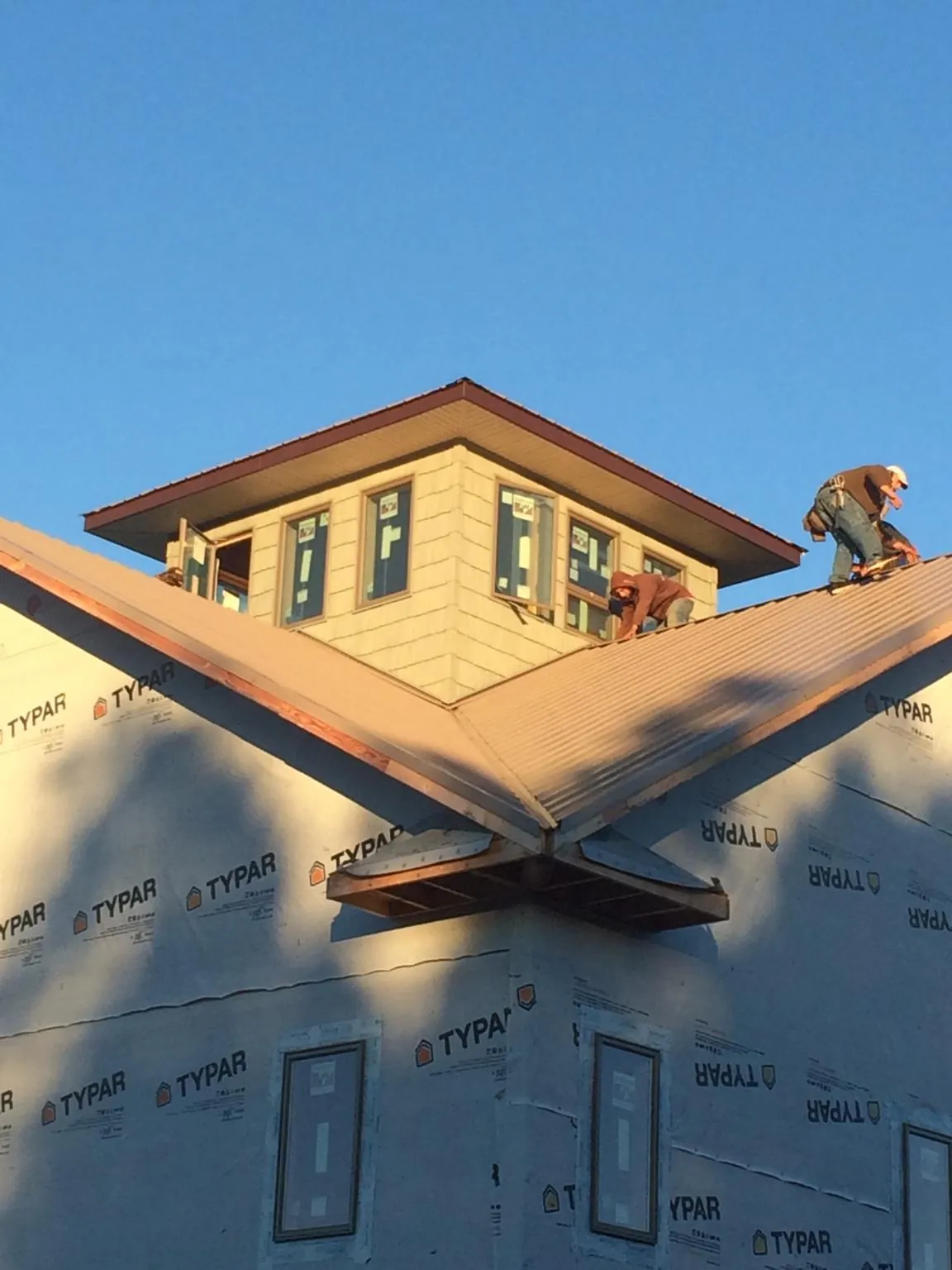 Roofers working around a rooftop cupola on a new metal roof at sunset — Roof Waterproofing in Chico by Roofing Brothers